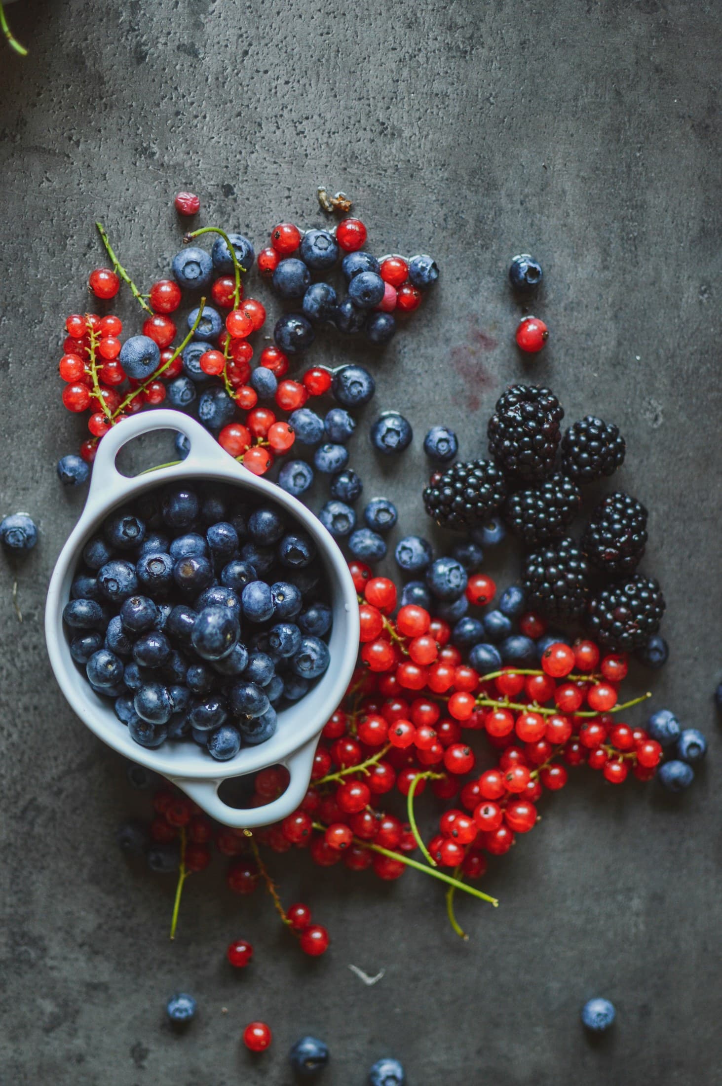 Blueberries, blackberries and redcurrants on a dark stone surface