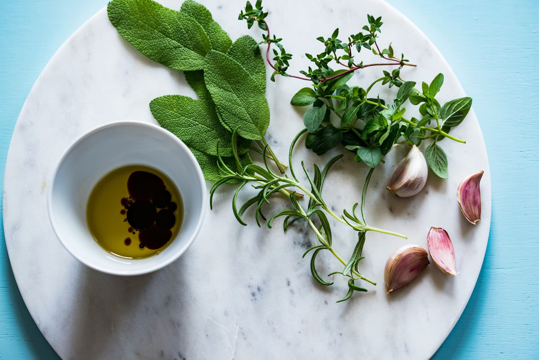 Fresh herbs, garlic and olive oil arranged on marble